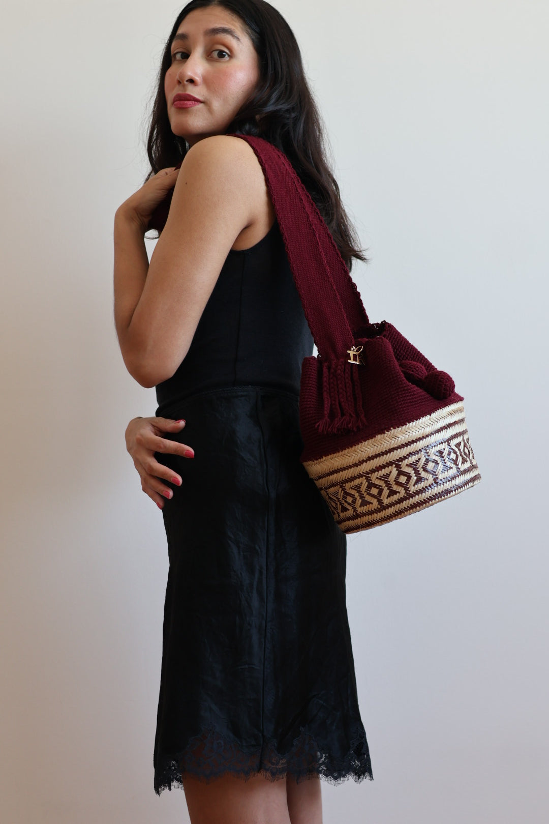 La Canasta Bag in burgundy by iiwa kashi, handcrafted by Wayuu artisans in Venezuela with cotton and caña brava, featuring 24K gold-plated logo.