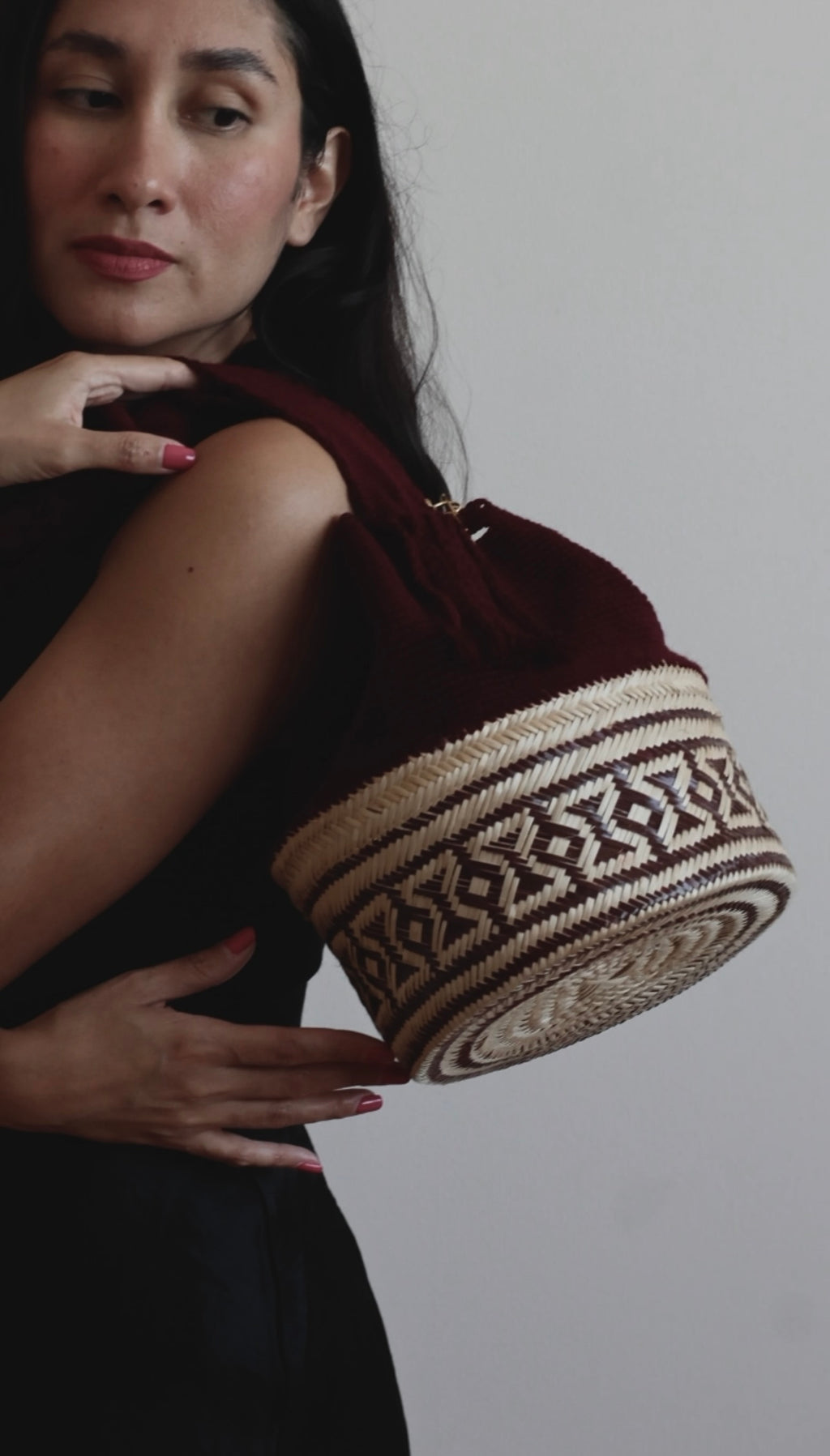 La Canasta Bag in burgundy by iiwa kashi, handcrafted by Wayuu artisans in Venezuela with cotton and caña brava, featuring 24K gold-plated logo.