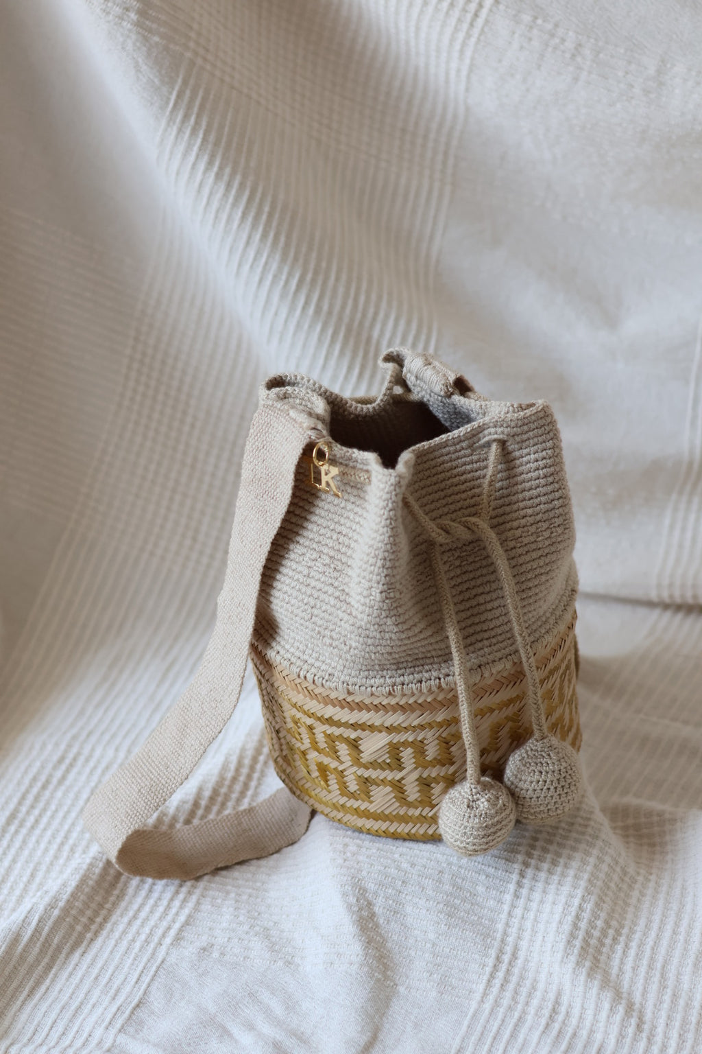 La Canasta Bag in beige by iiwa kashi, handcrafted by Wayuu artisans in Venezuela with cotton and caña brava, featuring 24K gold-plated logo.