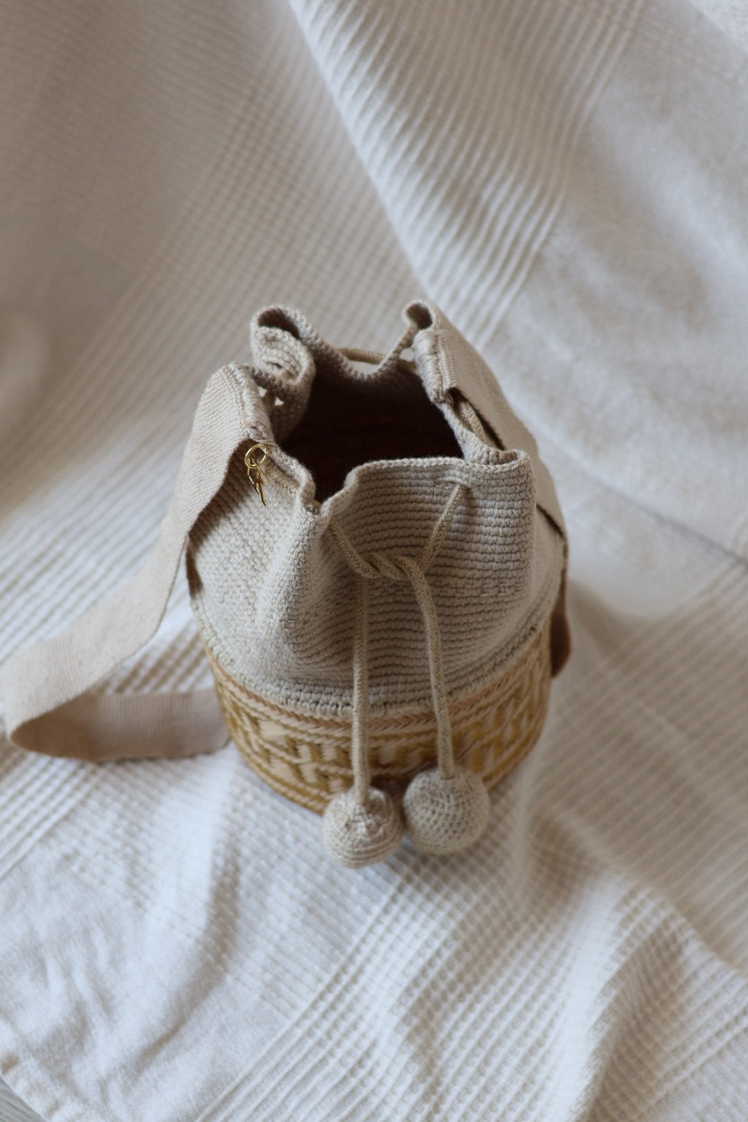 La Canasta Bag in beige by iiwa kashi, handcrafted by Wayuu artisans in Venezuela with cotton and caña brava, featuring 24K gold-plated logo.
