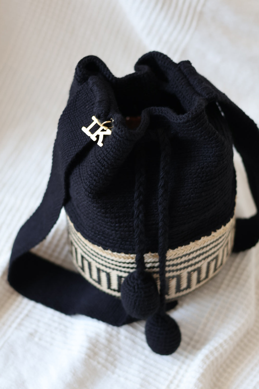 La Canasta Bag in black by iiwa kashi, handcrafted by Wayuu artisans in Venezuela with cotton and caña brava, featuring 24K gold-plated logo.
