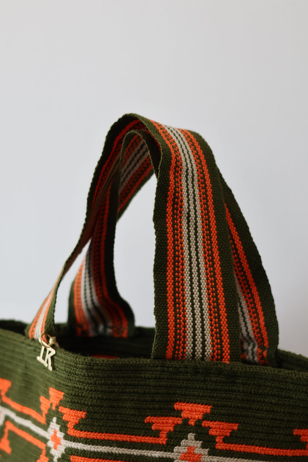 PALANACHI de la Tierra Wayuu Tote Bag in green and orange by iiwa kashi, handcrafted by Wayuu artisans from La Guajira, Venezuela, made with pure cotton and 24K gold-plated silver logo.