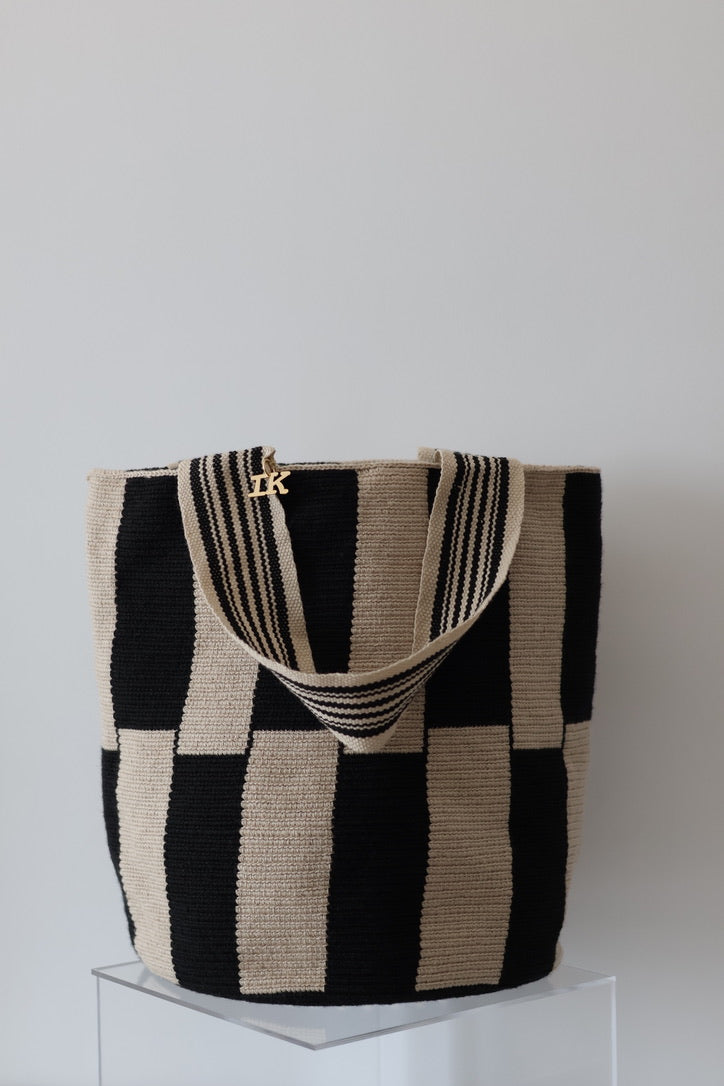 PALANACHI Stripped tote bag in beige and black by iiwa kashi, handcrafted by Wayuu artisans in La Guajira, Venezuela, made with pure cotton and 24K gold-plated silver logo.