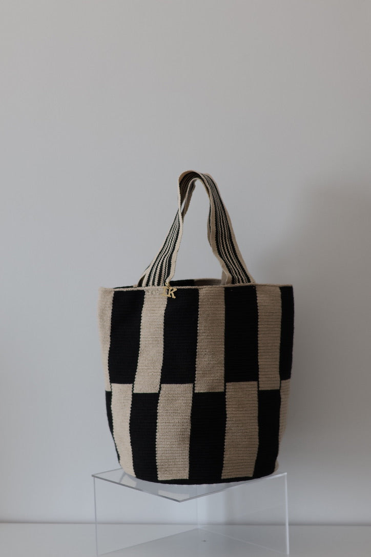 PALANACHI Stripped tote bag in beige and black by iiwa kashi, handcrafted by Wayuu artisans in La Guajira, Venezuela, made with pure cotton and 24K gold-plated silver logo.