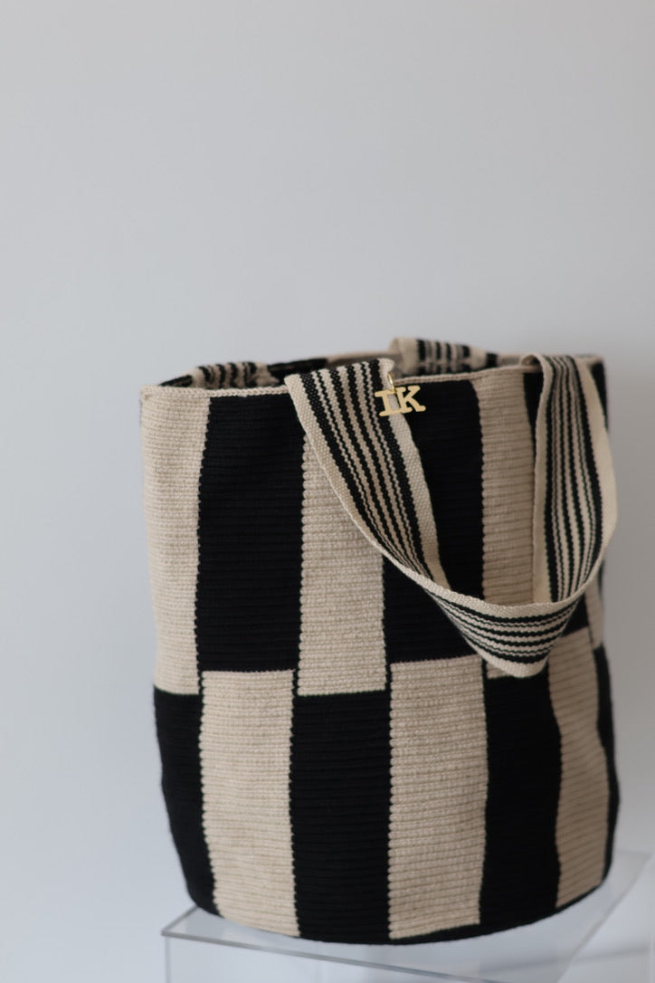 PALANACHI Stripped tote bag in beige and black by iiwa kashi, handcrafted by Wayuu artisans in La Guajira, Venezuela, made with pure cotton and 24K gold-plated silver logo.